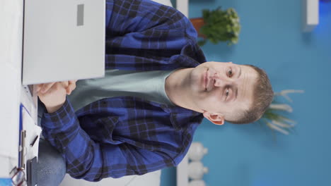 Vertical-video-of-Home-office-worker-man-looking-at-camera-depressed.